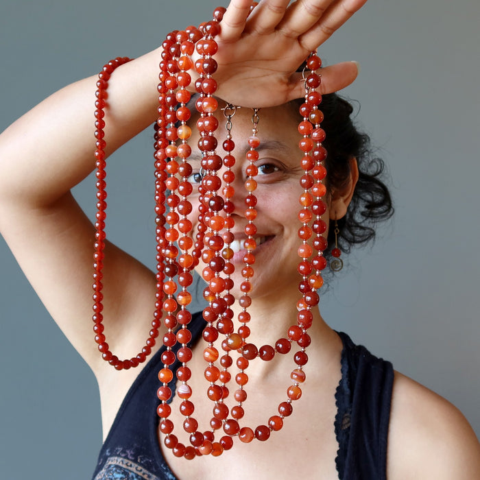 sheila of satin crystals holding orange carnelian necklaces