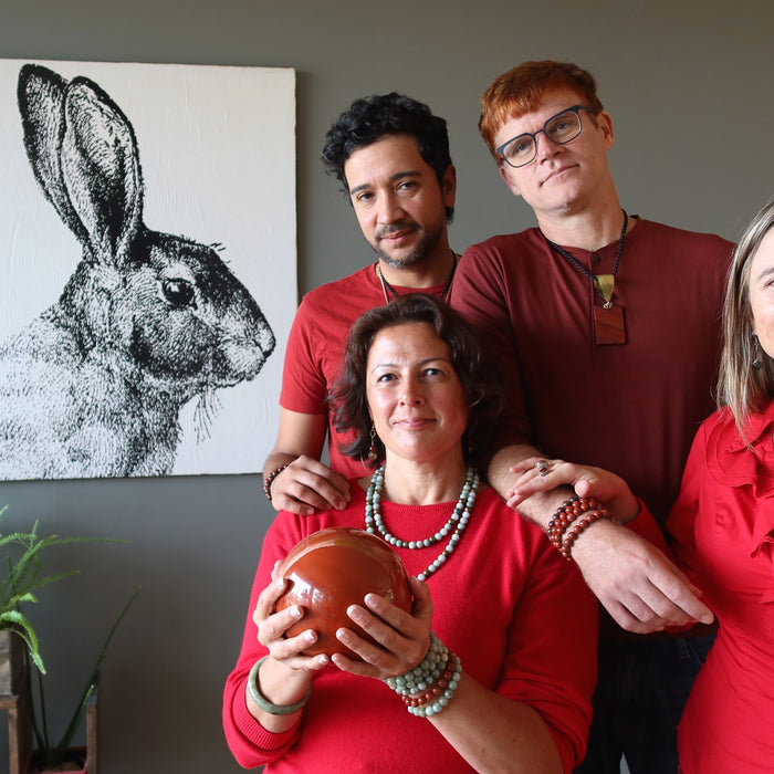 four people dressed in red wearing jade and holding red jasper, rabbit picture on the wall