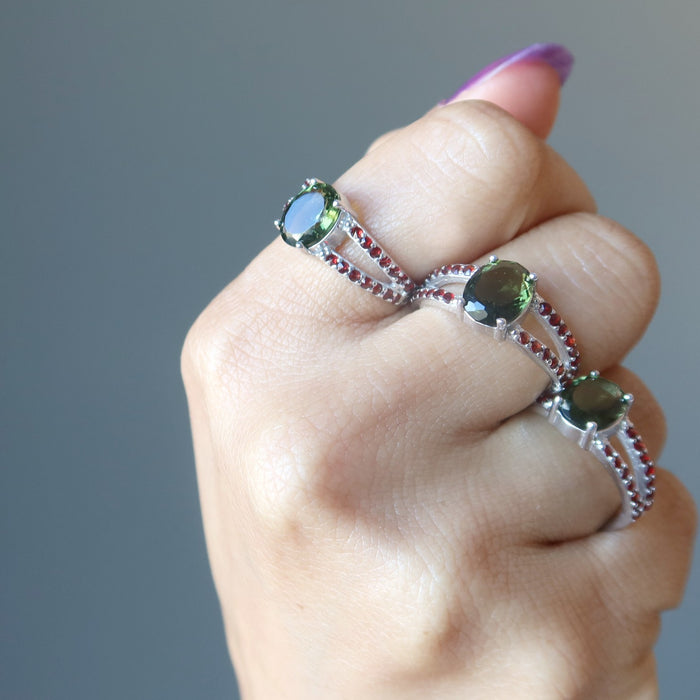 hand wearing three moldavite garnet rings