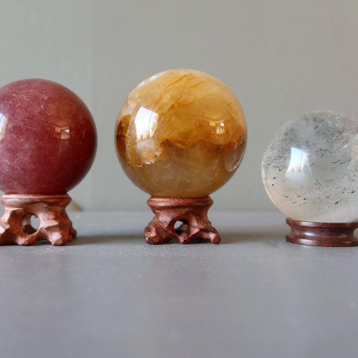 pink, golden, included quartz spheres on wood stands