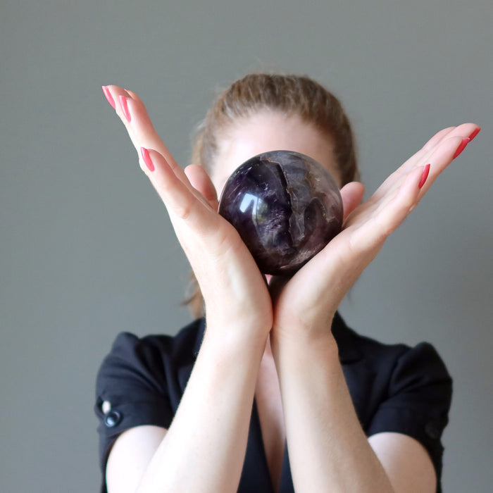 jamie of satin crystals with an amethyst sphere in front of her face