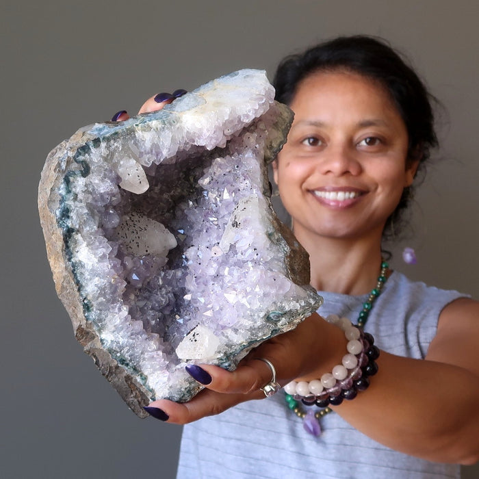 sheila of satin crystals holding up a large amethyst geode 