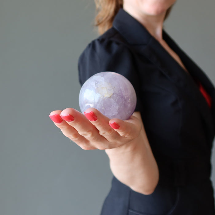 female holding a light purple amethyst sphere