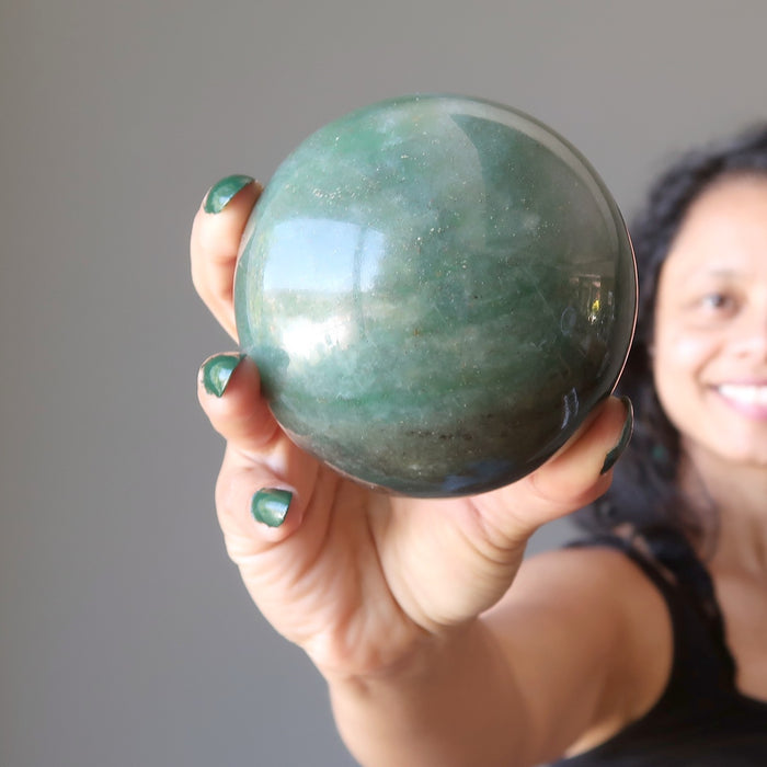sheila of satin crystals holding out a green aventurine sphere