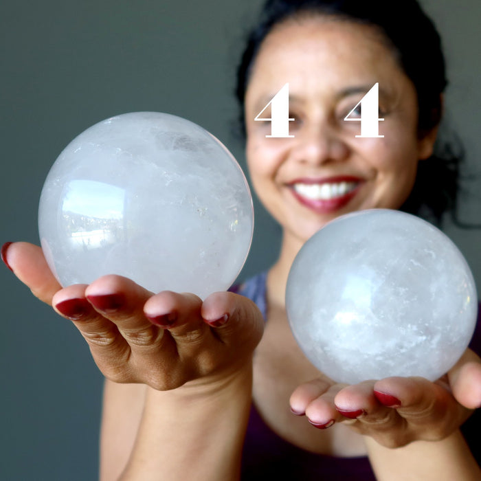 woman with 4's over her eyes holding big quartz crystal balls