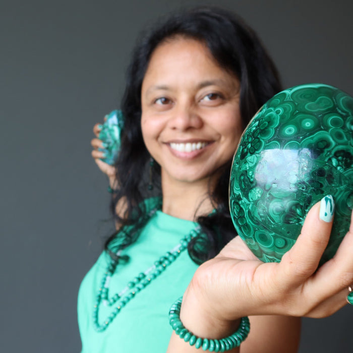 Can you benefit from Malachite? sheila of satin crystals holding a malachite egg and polished stone