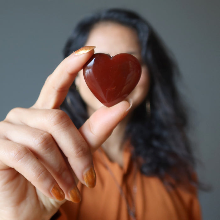 woman with orange carnelian heart in front of her face