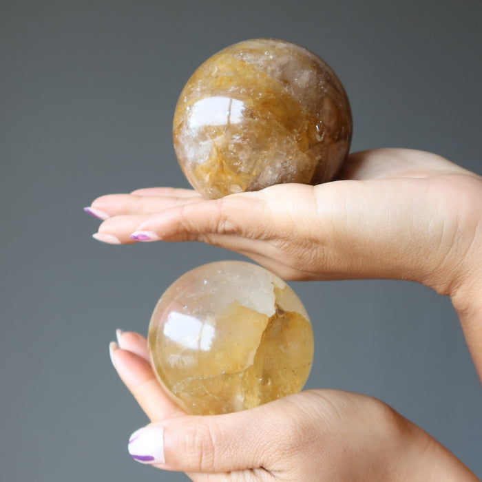 hands holding golden quartz spheres