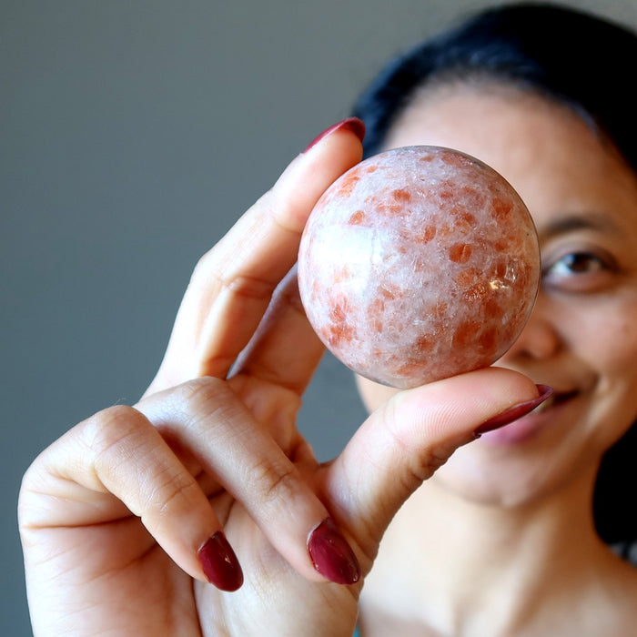 sheila of satin crystals holding up a sunstone sphere