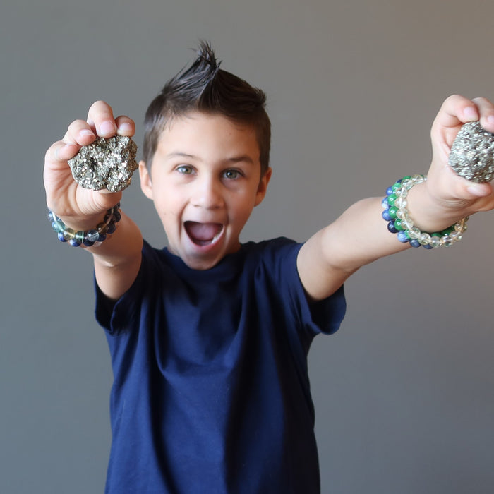 kid holding out two pyrite crystals
