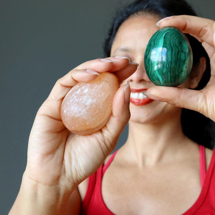sheila of satin crystals holding an orange selenite and a green malachite egg