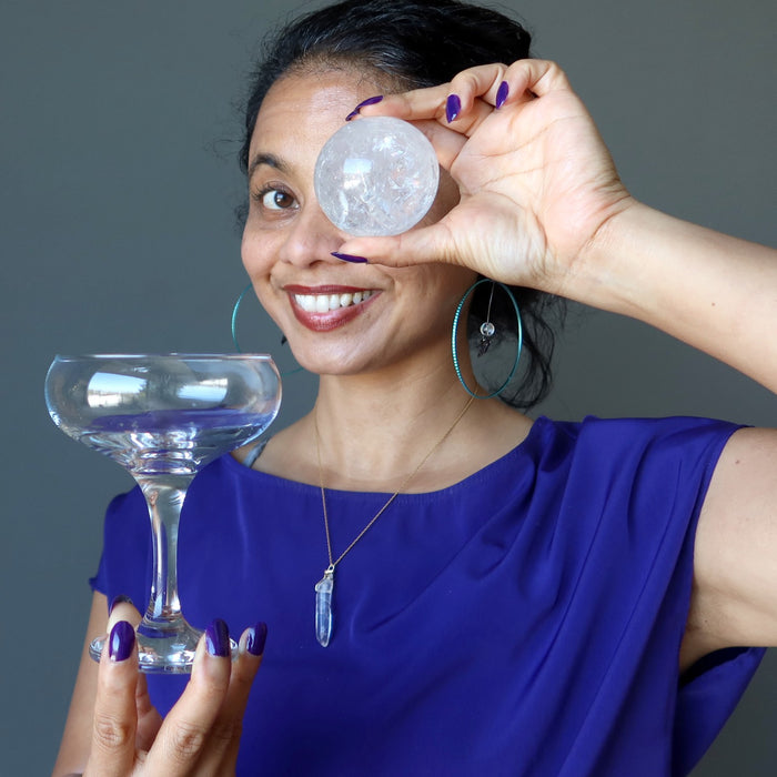 sheila of satin crystals holding up a martini glass and a clear quartz sphere