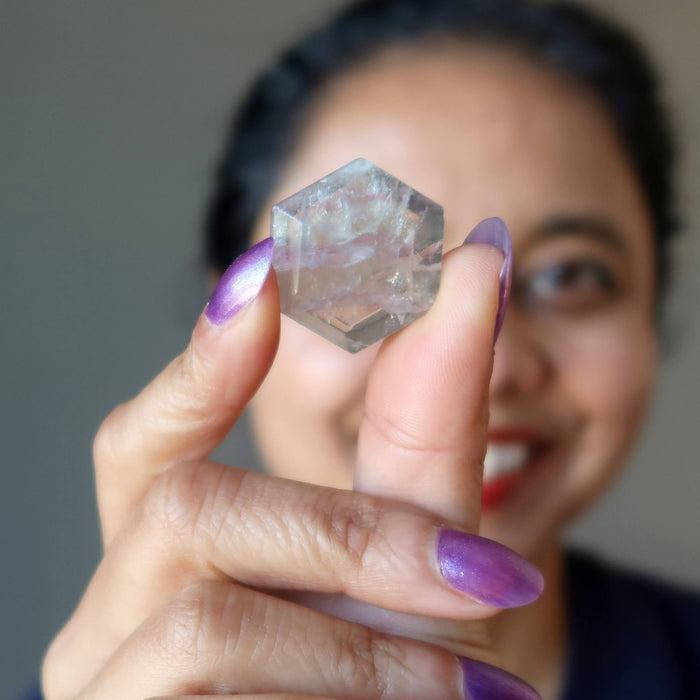 sheila of satin crystals holding up a fluorite hexagon cabochon