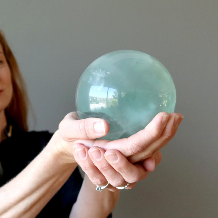woman holdng green fluorite sphere
