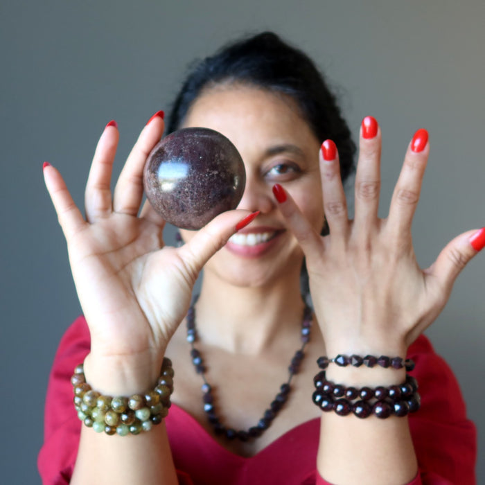 sheila of satin crystals wearing and holding garnet stones