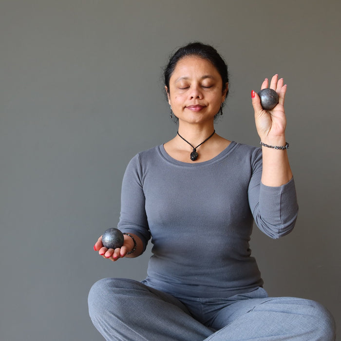 woman meditating with hematite spheres