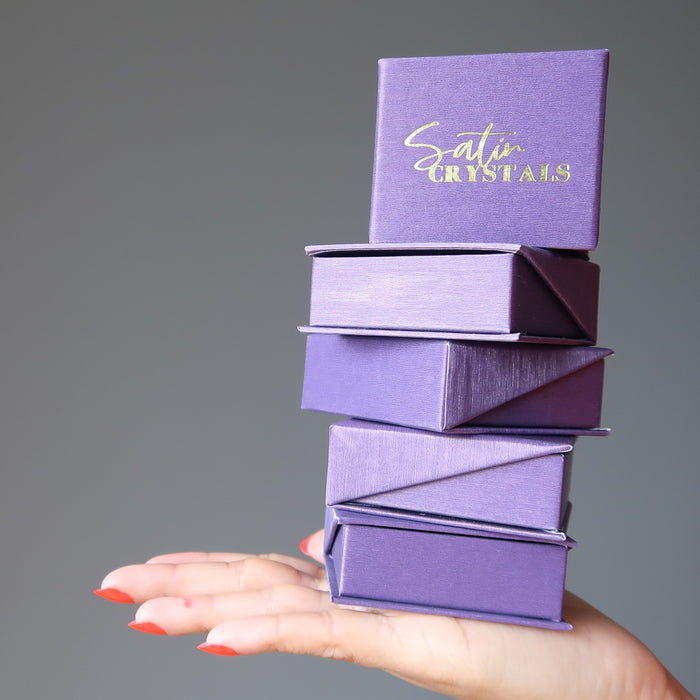 hand holding satin crystals purple boxes