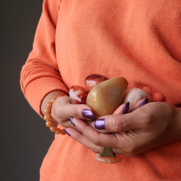 woman holding orange carnelian crystals to her belly