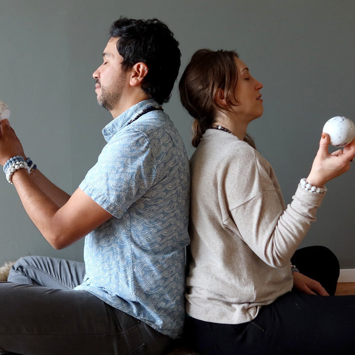 man and woman back to back meditating with howlite spheres