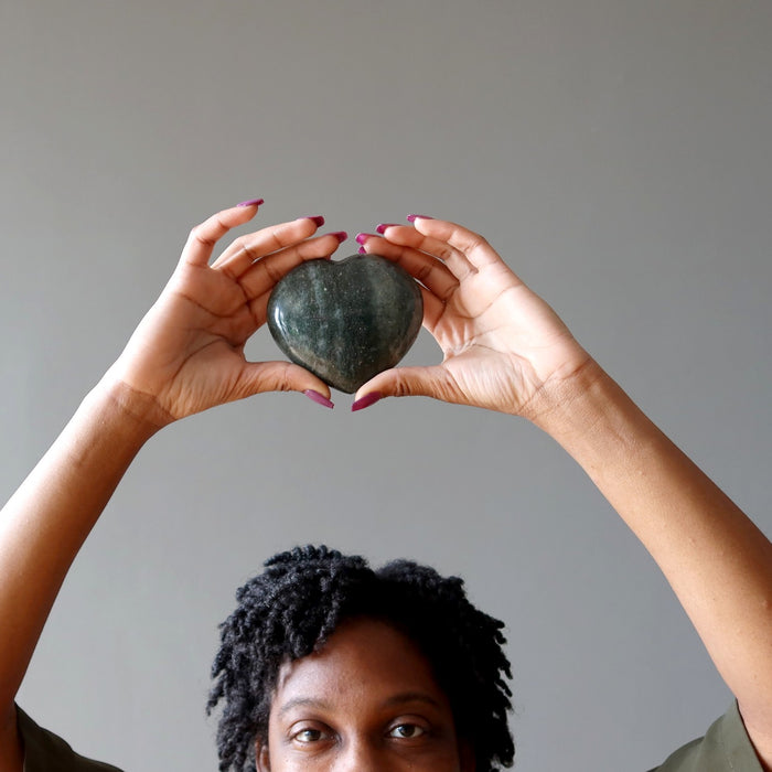 woman holding green aventurine heart above head