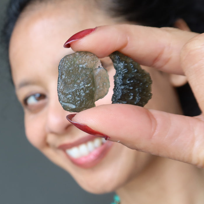 sheila of satin crystals holding up two moldavite stones