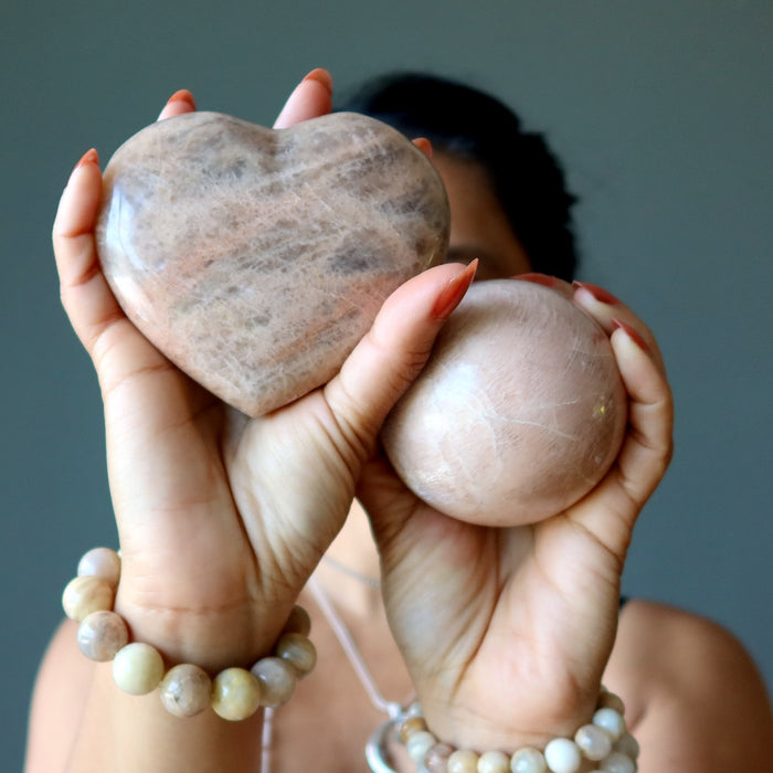 woman holding peach moonstone heart and sphere