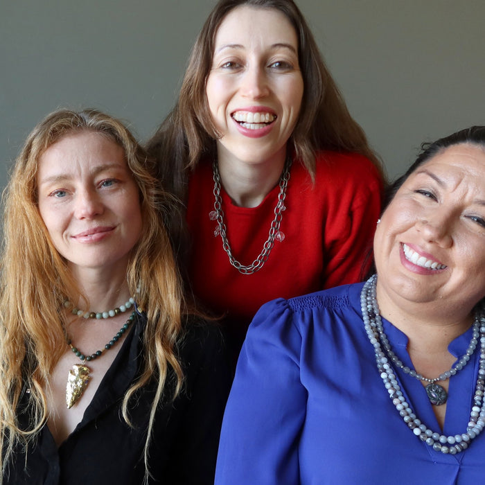three women wearing crystal healing necklaces