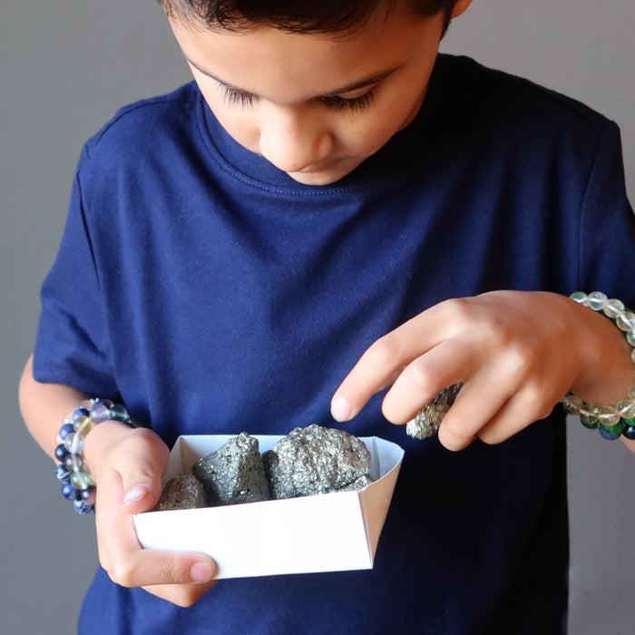 boy picking out pyrite clusters from a box