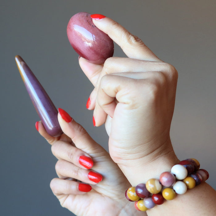 hands wearing mookaite jasper bracelets, holding a mookaite jasper oval and massage wand