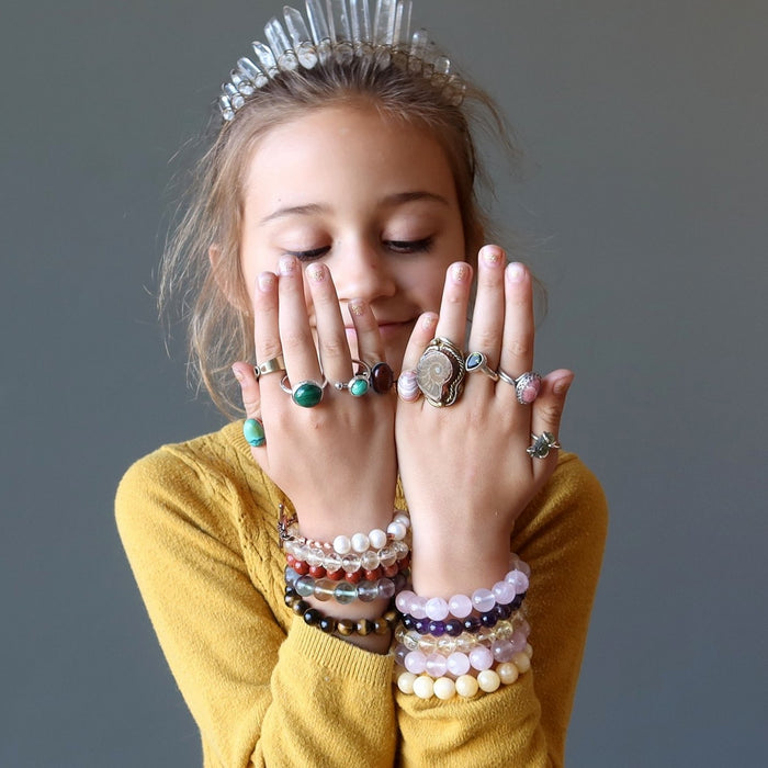 girl wearing a lot of bracelets, jewelry and quartz crown