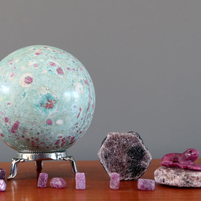 ruby fuchsite sphere and ruby raw stones on shelf