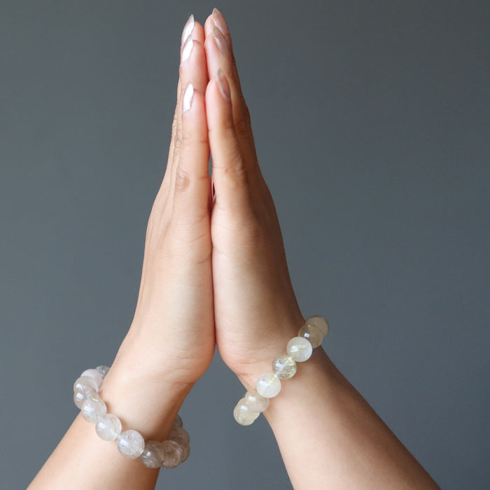 hands in prayer wearing golden rutilated quartz bracelets