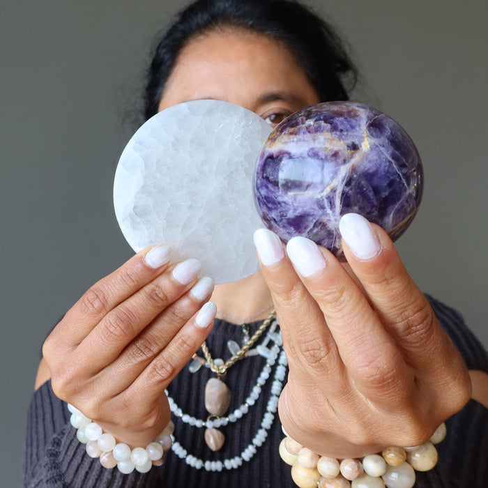 woman holding selenite circle and amethyst sphere