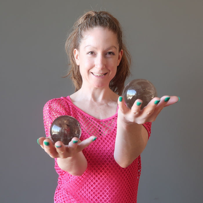 woman holding two smoky quartz spheres