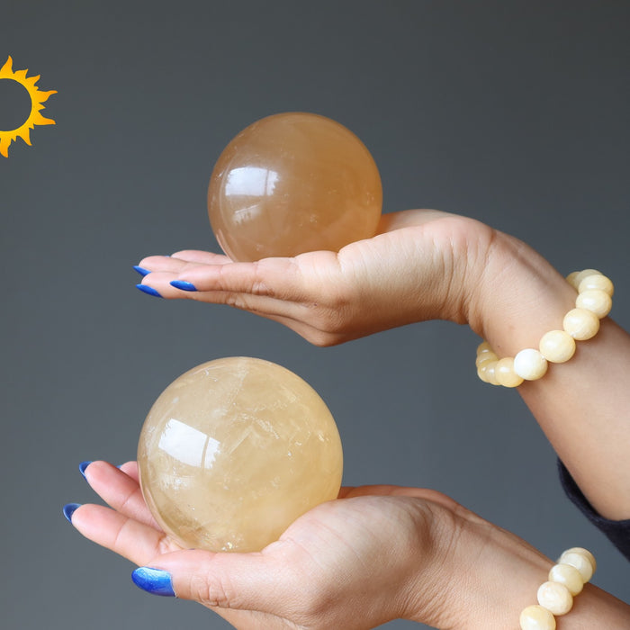 hands holding golden calcite spheres and wearing yellow calcite bracelets