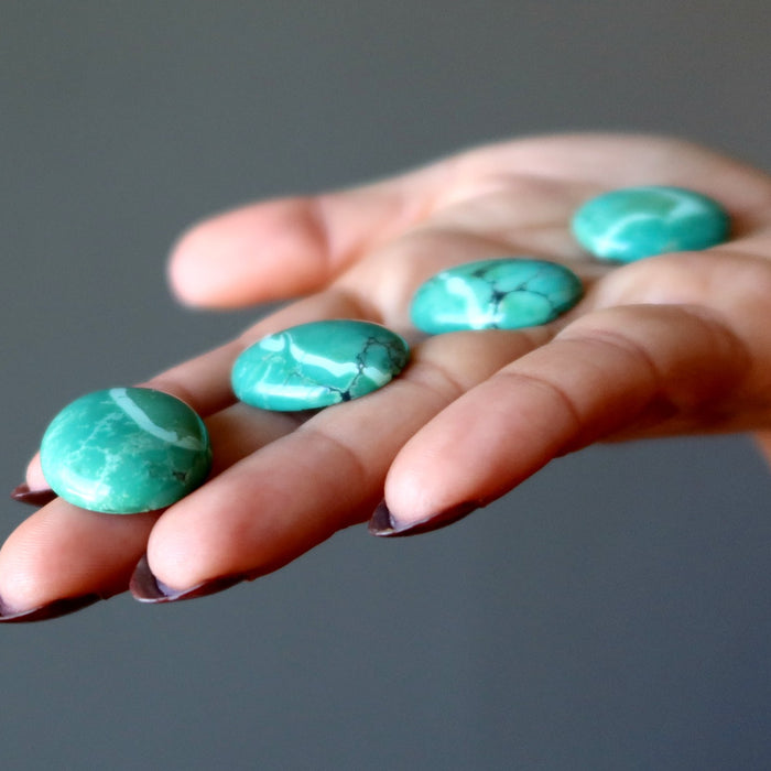four turquoise cabochons in palm of hand