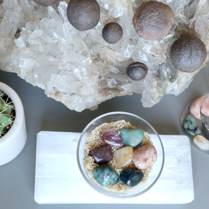 tumbled stones and moqui balls on quartz cluster, selenite slab, in water, in a cactus pot and on brown rice