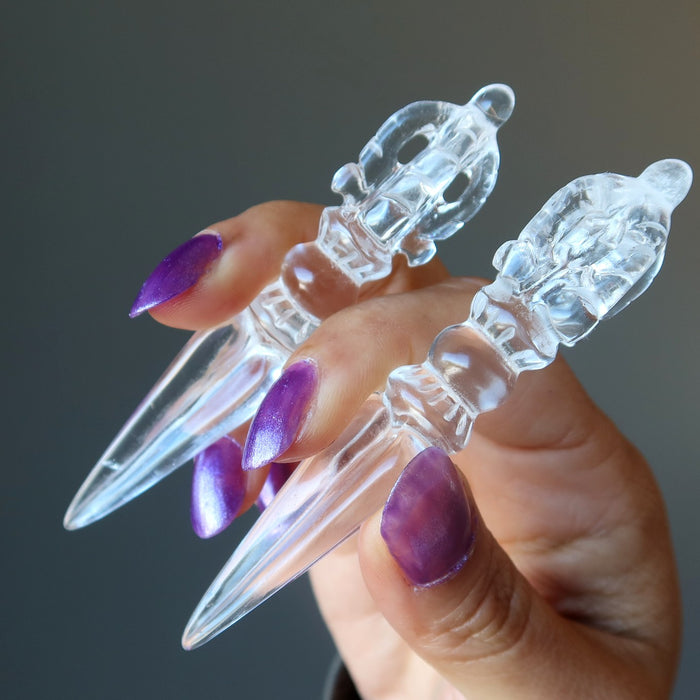hand holding two clear quartz phurba wands
