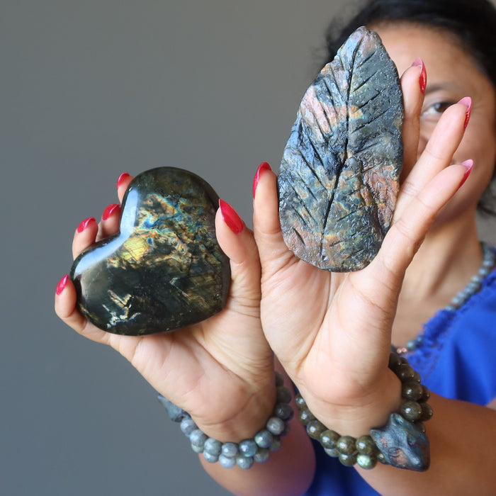 female holding up a labradorite heart and leaf stone