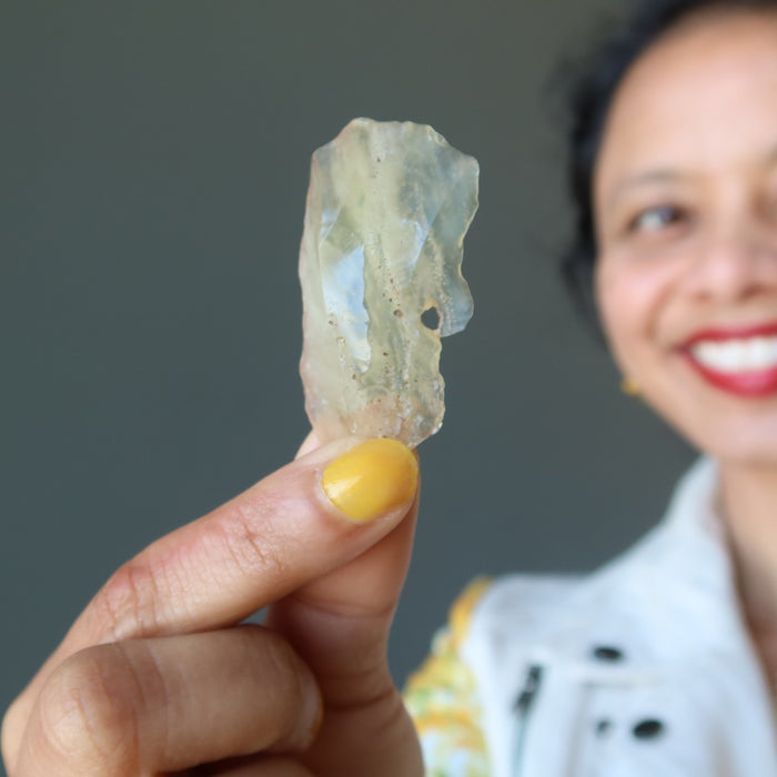 sheila of satin crystals holding raw yellow libyan desert glass specimen