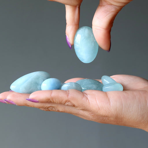 blue aquamarine tumbled stones in hand