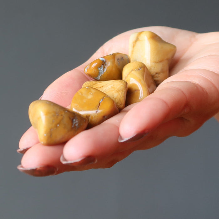 hand holding yellow jasper tumbled stones