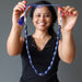 woman holding lapis beaded necklace