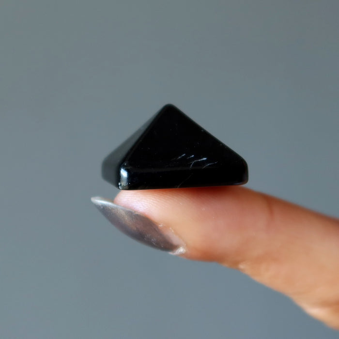 black obsidian pyramid on finger
