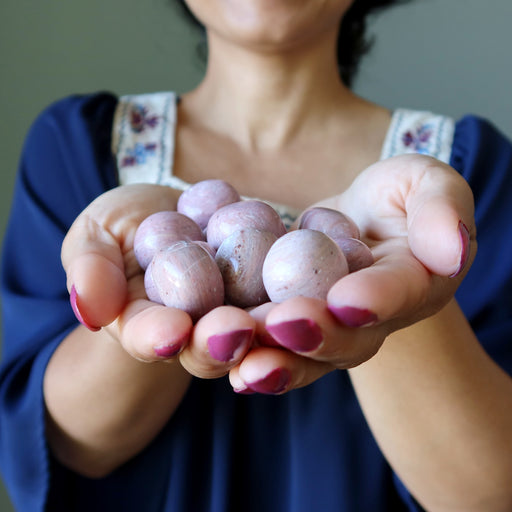 pink opal tumbled stones in palm of hands