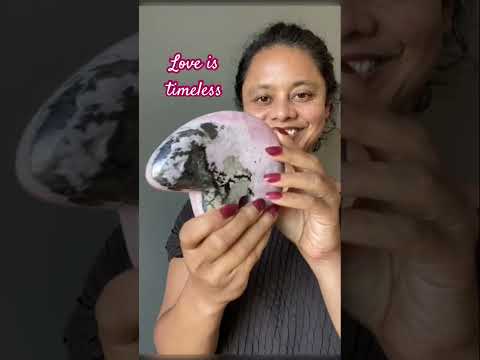 video on woman holding large rhodonite bear crystal
