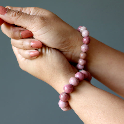 hands wearing rhodonite bracelets