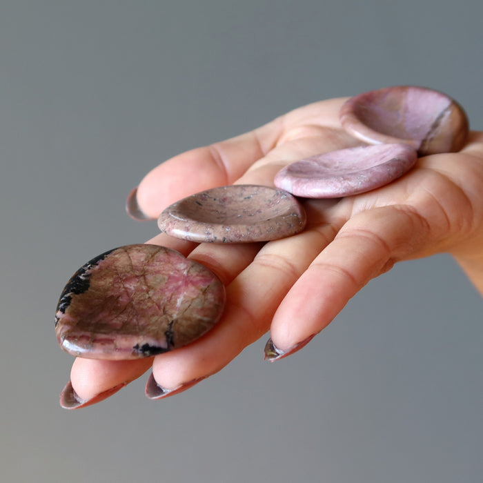 Displaying 4 Pink Rhodonite Worry Stones on the palm