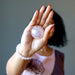 woman holding aura rose quartz sphere