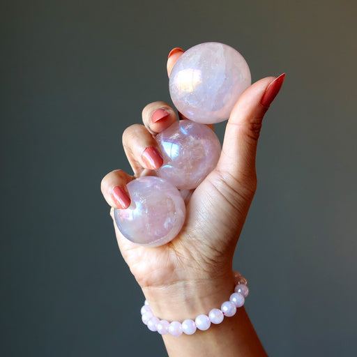 three aura rose quartz spheres and bracelet on hand